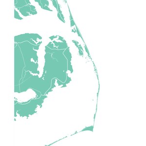 May include: A minimalist map of the Outer Banks in a teal color, with white lines indicating roads and waterways. The text "Outer Banks" is printed in a matching teal color at the bottom of the image. The map is set against a white background.