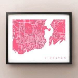 May include: A framed print featuring a map of Kingston, Ontario, in a vibrant pink hue. The city's streets and waterways are depicted in white against the pink background. The word "KINGSTON" is printed in pink at the bottom.