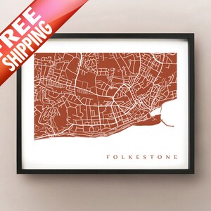 Könnte beinhalten: Gerahmter Druck mit einer detaillierten Karte von Folkestone in Rostrot mit weißen Linien, die Straßen und Gebäude darstellen. Der Name der Stadt ist in einer Serifenschrift gedruckt. Der Druck ist in einem schwarzen Rahmen.
