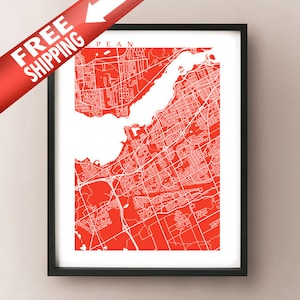 Puede incluir: Impresión enmarcada de un mapa rojo y blanco de una ciudad, con el nombre de la ciudad en la parte superior. El mapa presenta un diseño detallado de las calles y una gran masa de agua. Una pancarta roja con las palabras "FREE SHIPPING" está en la esquina superior izquierda.