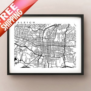 May include: Black and white map of Raleigh, North Carolina, framed in a black border. The map shows the city's streets and roads in a detailed, minimalist style. The word "RALEIGH" is printed at the top of the map.