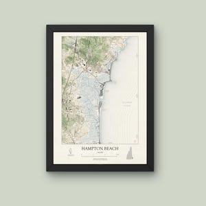 May include: Framed map print of Hampton Beach, New Hampshire, featuring detailed cartography in muted tones of green, beige, and blue. The map includes the Atlantic Ocean and local topography, with the text "Hampton Beach" at the bottom.