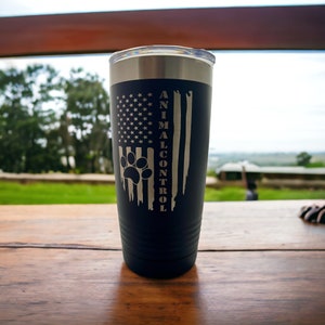 May include: A blue stainless steel tumbler with a paw print and the words "ANIMAL CONTROL" on a distressed American flag design.
