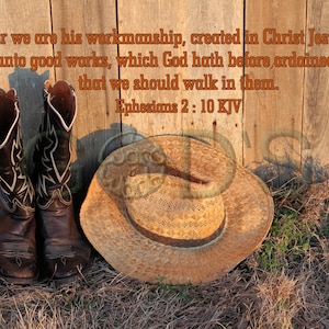 以下が含まれることがあります： 木製のフェンスの前に、乾いた草の上に、茶色のカウボーイブーツと麦わら帽子のカウボーイハットが置かれています。フェンスには「For we are his workmanship, created in Christ Jesus unto good works, which God hath before ordained that we should walk in them. Ephesians 2: 10 KJV」という文章が書かれています。