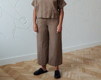 May include: A person wearing a brown linen top and matching wide-leg pants. The outfit is a relaxed and comfortable style.