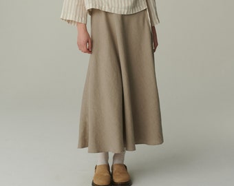May include: A woman is wearing a striped linen wrap top and a long, flowing linen skirt. She is wearing brown leather shoes.