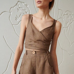 May include: A brown linen wrap top and wide-leg pants set. The top has a V-neckline and a wrap closure at the waist. The pants have a high waist and side pockets.