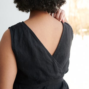 May include: A black linen sleeveless dress with a deep V-neckline and a wrap-style bodice. The dress has a belt at the waist.