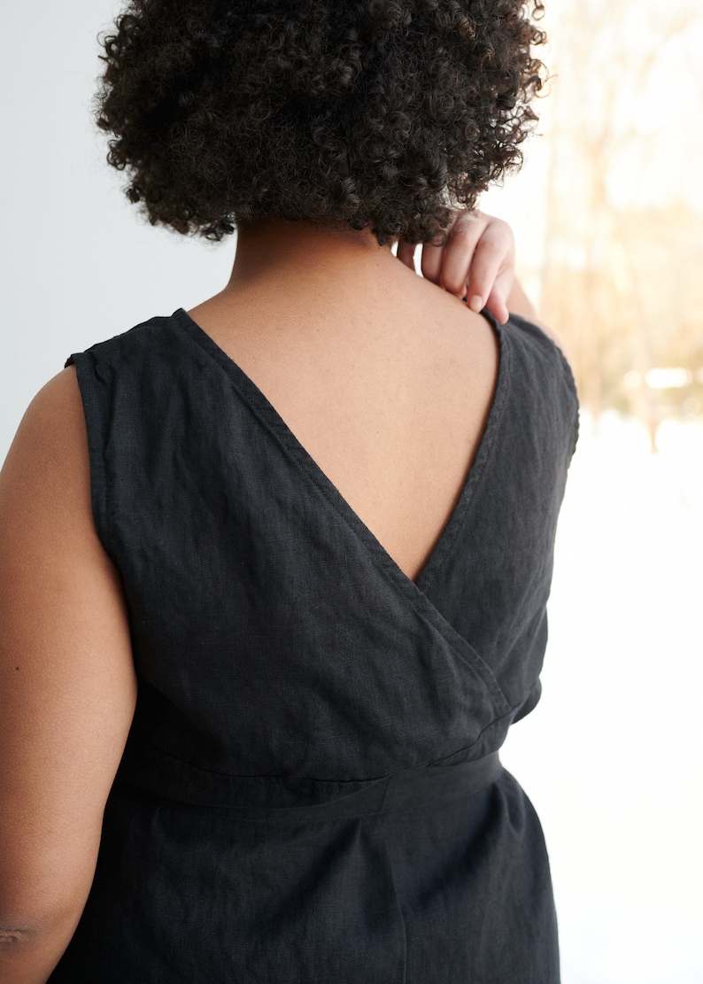 May include: A black linen sleeveless dress with a deep V-neckline and a wrap-style bodice. The dress has a belt at the waist.