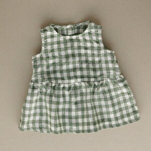 Puede incluir: Un vestido sin mangas de cuadros vichy verde y blanco con un dobladillo con volantes.
