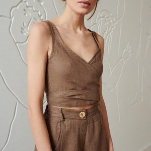 May include: A brown linen wrap top and matching wide-leg pants. The top has a V-neck and ties at the waist. The pants have a high waist and pockets.