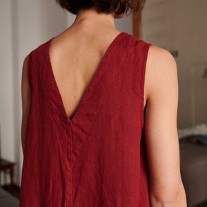 May include: A sleeveless, deep V-neck dress in a rich burgundy color. The dress is made of a soft, linen fabric and has a relaxed, flowy fit.