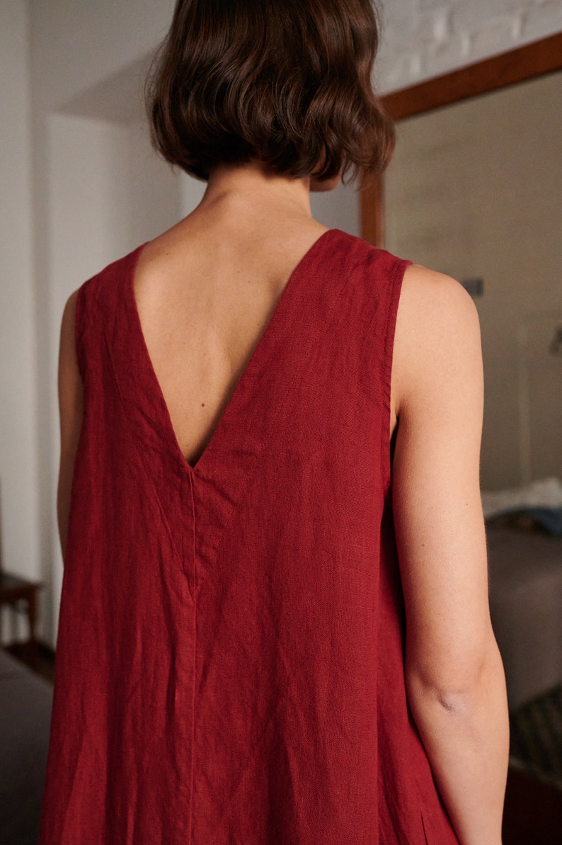 May include: A sleeveless, deep V-neck dress in a rich burgundy color. The dress is made of a soft, linen fabric and has a relaxed, flowy fit.