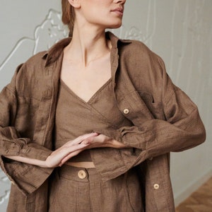 May include: A brown linen shirt, top, and pants set. The shirt has a button-down collar and long sleeves. The top is a wrap style with a V-neck. The pants are high-waisted and have a wide leg.