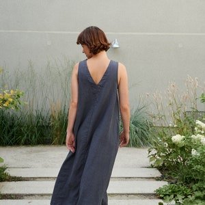 Puede incluir: Una mujer con un vestido de lino sin mangas de color gris oscuro caminando por un tramo de escaleras de hormig&oacute;n.