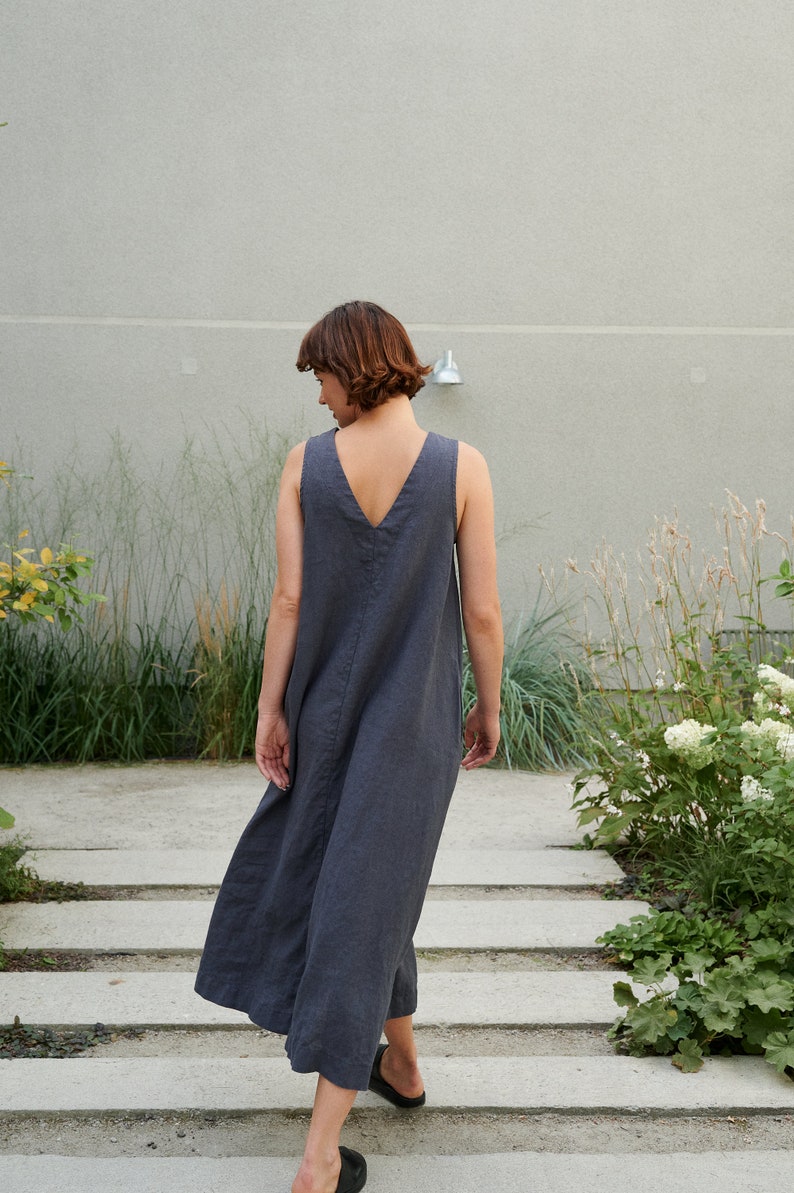 Puede incluir: Una mujer con un vestido de lino sin mangas de color gris oscuro caminando por un tramo de escaleras de hormig&oacute;n.