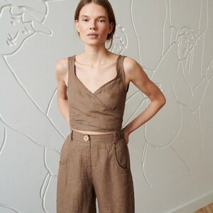 May include: A brown linen wrap top and wide-leg pants set. The top has a V-neckline and a wrap closure at the waist. The pants have a high waist and wide legs.