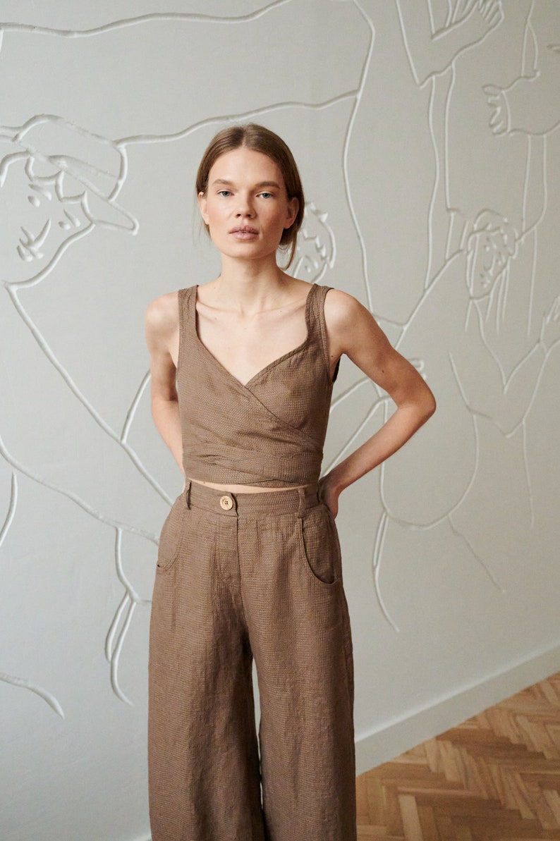 May include: A brown linen wrap top and wide-leg pants set. The top has a V-neckline and a wrap closure at the waist. The pants have a high waist and wide legs.