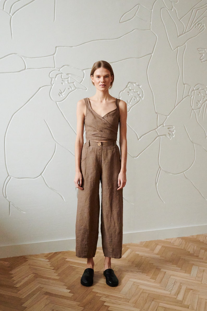May include: A brown linen wrap top and wide-leg pants set. The top has a V-neckline and a wrap closure at the waist. The pants have a high waist and a wide leg.