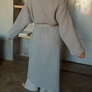 May include: A gray waffle-weave robe with a self-tie belt. The robe is long and has long sleeves.