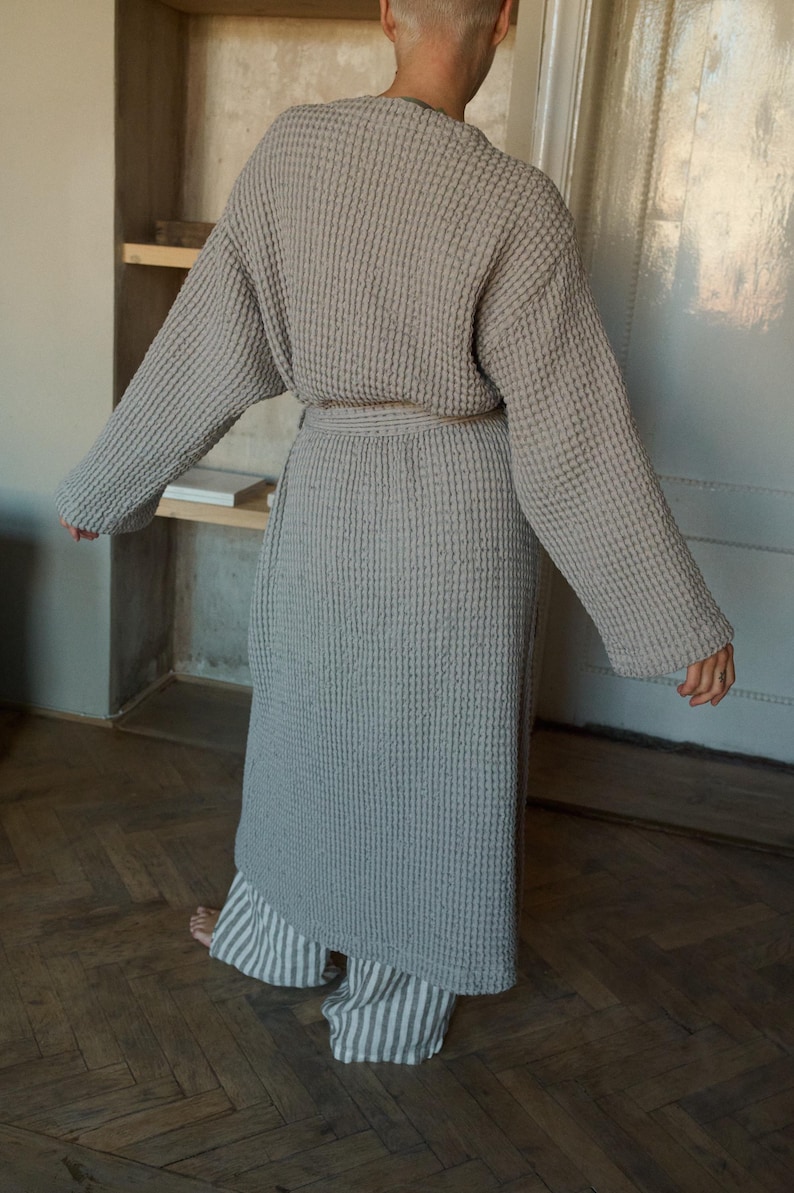 May include: A gray waffle-weave robe with a self-tie belt. The robe is long and has long sleeves.