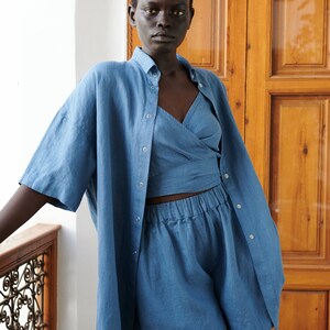 May include: A blue linen shirt and matching shorts set. The shirt has a button-down front and short sleeves. The shorts have an elastic waistband and a relaxed fit.