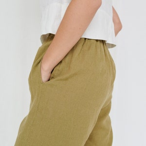 K&ouml;nnte beinhalten: Eine olivgr&uuml;ne Leinenhose mit Kordelzugbund und Taschen. Die Hose ist locker geschnitten und hat eine lockere Silhouette.