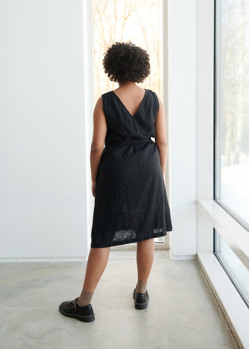May include: A black linen wrap dress with a V-neckline and a tie belt. The dress is knee-length and has a relaxed fit.