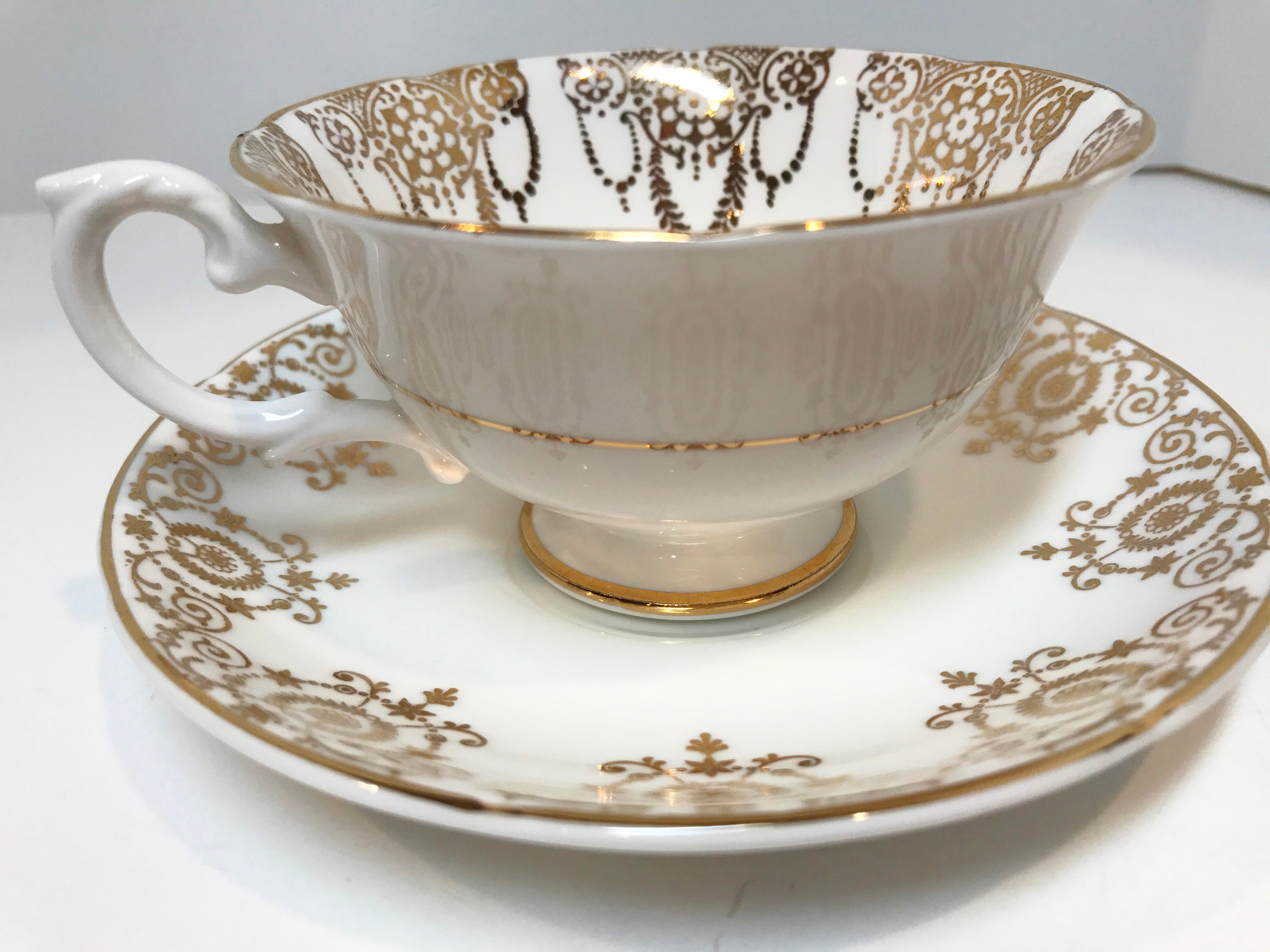 white and gold cup and saucer