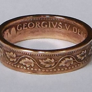 May include: A copper-colored ring with a decorative design of leaves and the inscription "GEORGIVS V DEI" around the band.