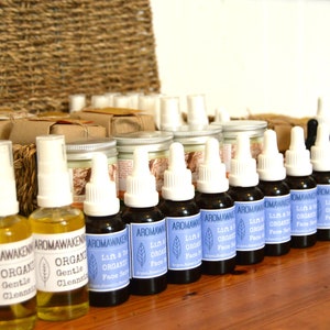 K&ouml;nnte beinhalten: Eine Sammlung von Aromawakening-Hautpflegeprodukten, bestehend aus durchsichtigen Spr&uuml;hflaschen mit gelber Fl&uuml;ssigkeit, dunklen Braunglas-Tropfflaschen mit blauen Etiketten Lift & Tone Organic Face Serum und Braunglasflaschen mit Hemp-Etikett.