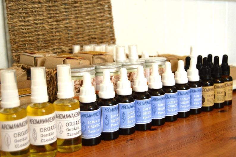 K&ouml;nnte beinhalten: Eine Sammlung von Aromawakening-Hautpflegeprodukten, bestehend aus durchsichtigen Spr&uuml;hflaschen mit gelber Fl&uuml;ssigkeit, dunklen Braunglas-Tropfflaschen mit blauen Etiketten Lift & Tone Organic Face Serum und Braunglasflaschen mit Hemp-Etikett.