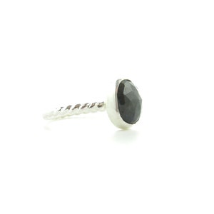 K&ouml;nnte beinhalten: Ein silberner Ring mit einem gedrehten Band und einem schwarzen Edelstein.