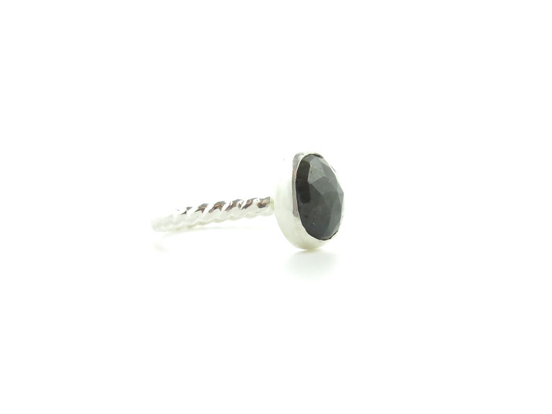 K&ouml;nnte beinhalten: Ein silberner Ring mit einem gedrehten Band und einem schwarzen Edelstein.