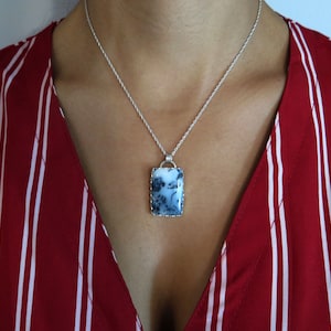 May include: A silver chain necklace with a rectangular pendant featuring a blue and white agate stone.