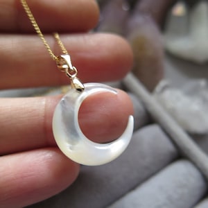 Può includere: Una collana con catena dorata con un ciondolo a forma di mezzaluna bianca in madreperla.