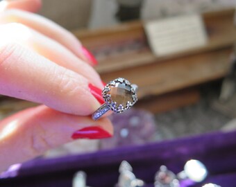 May include: A silver ring with a brown gemstone set in a delicate floral design.