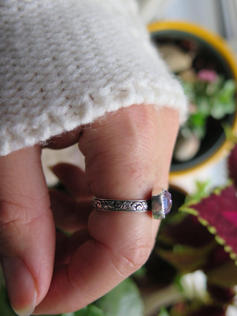 May include: A silver ring with a purple gemstone set in a floral design.