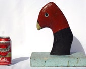 An odd folk art concrete bird. It is hand made. The piece is painted black and reddish brown, with yellowish beak and pale blue on the base.