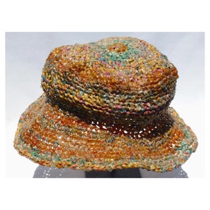 May include: A multi-colored crocheted hat made from woven straw. The hat has a wide brim and is a light brown color with hints of pink, blue, and green.