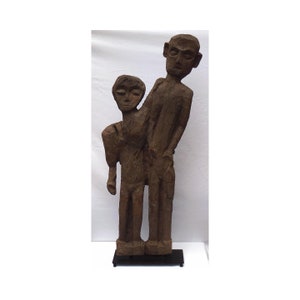 A 4 foot primitive stylized carving of 2 people expressively carved from 1 slab of wood, mounted on a custom made base. (Offers Considered)