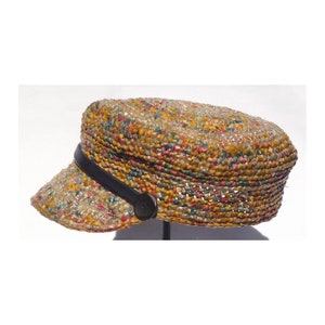 May include: A multi-colored crocheted hat with a black leather band and a brown button. The hat has a rounded crown and a wide brim.