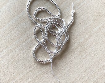 May include: A silver-colored strand of seed beads, perfect for jewelry making or crafting projects.