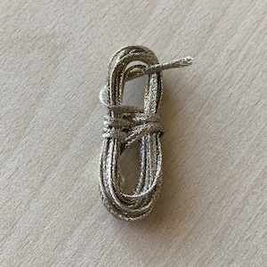 Puede incluir: Un rollo de cordón metálico dorado, perfecto para añadir un toque de brillo a las manualidades y decoraciones.