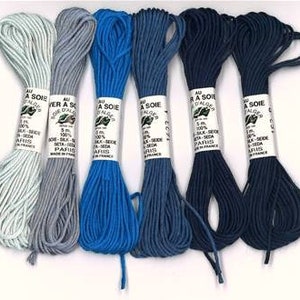 Peut inclure: Six bobines de fil de soie dans différentes nuances de bleu et de gris. Chaque bobine est étiquetée "Au fil a Soie" et "Soie d'Alsace".