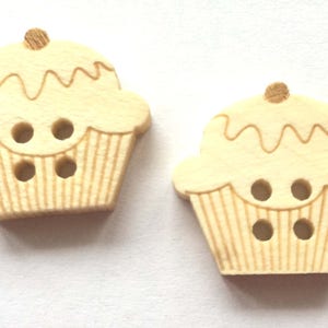 Peut inclure: Deux boutons en bois en forme de cupcake de couleur brun clair avec un glaçage blanc. Les boutons ont trois trous chacun.