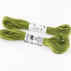 Op de afbeelding: Twee spoelen groene zijden borduurgaren, elk 5 meter lang. Het etiket vermeldt "Au Ver A Sole" en "100% Zijde - Seta-Seide - Seda - Seda".