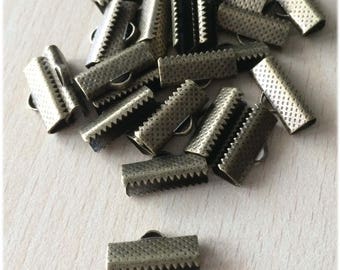 May include: A pile of 16 mm antique brass metal cord end caps. The caps have a textured surface and a small loop on one end.