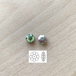 May include: Two green flower-shaped rhinestones with a silver backing. The rhinestones are shown next to a diagram of the rhinestone.