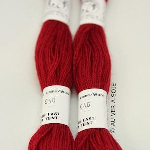 May include: Two spools of red wool embroidery floss with white labels that read "Laine/Wool 946 JR FAST TEINT" and "Fabrique AU VER A SOIE".